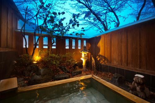 a hot tub in a garden at night at Shima Onsen Kashiwaya Ryokan in Nakanojo