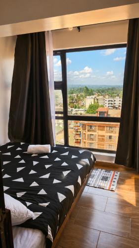 a bed in a room with a large window at Starla Apartment in Kinoo