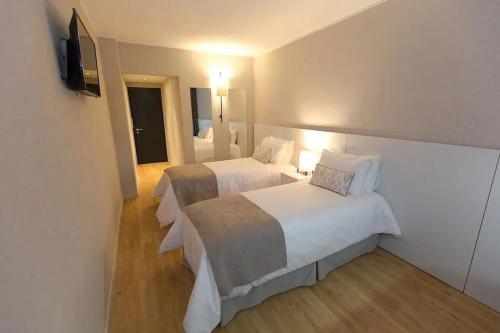 ein Hotelzimmer mit zwei Betten und einem Flachbildfernseher in der Unterkunft Hotel Flores in Trinidad