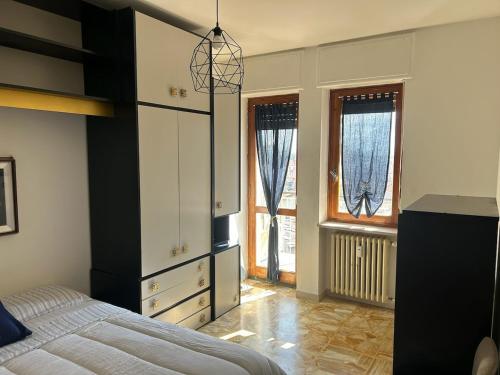 a bedroom with a bed and a dresser and windows at Alpine penthouse, breathtaking views! in Bussoleno