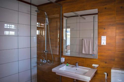 a bathroom with a sink and a shower and a mirror at Mount Mary Inn in Nuwara Eliya