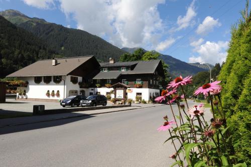 a building on the side of a road with flowers at Pension Backstuba in Partenen