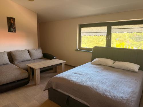 a bedroom with a bed and a couch and a window at Guest House Atostogana in Druskininkai
