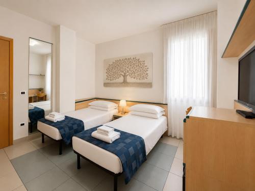 a hotel room with two beds and a television at Domus Ciliota in Venice