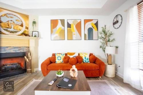 a living room with a orange couch and a fireplace at Sunrise Tranquil Cottage 3BR RAFB Pet Friendly in Warner Robins