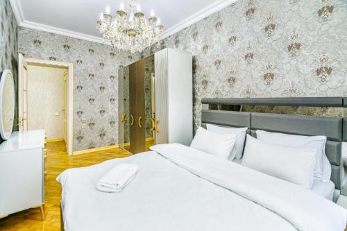 a bedroom with a white bed and a chandelier at Kolorit Modern Apartment in Baku