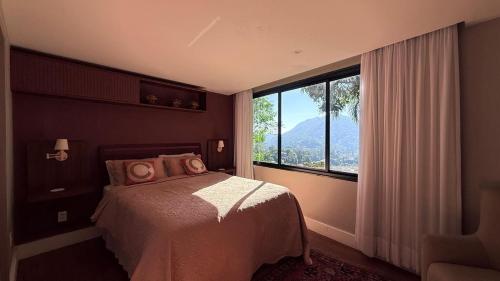 a bedroom with a bed and a large window at BELA VISTA RESERVAs in Petrópolis