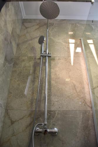 a shower head in a room with a stone floor at Saonia Apartment in Samothraki