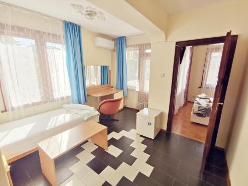 a room with a bed and a desk and window at Hotel VALDI in Ahtopol