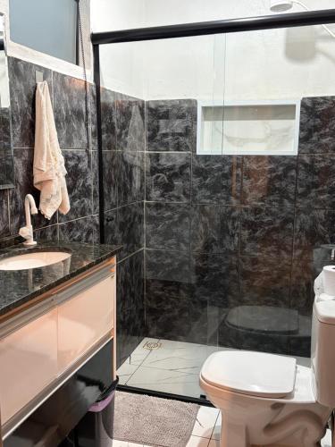 a bathroom with a toilet and a glass shower at Aconchego Central in Tiradentes