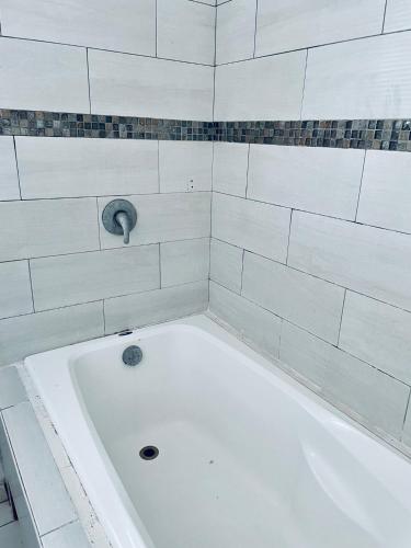 a white bath tub in a white tiled bathroom at Economic Apartments & Rooms next to the beach in Cancún