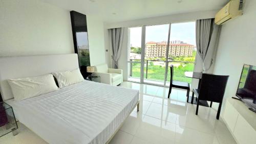 a bedroom with a white bed and a large window at City Center Residence NEW in Pattaya