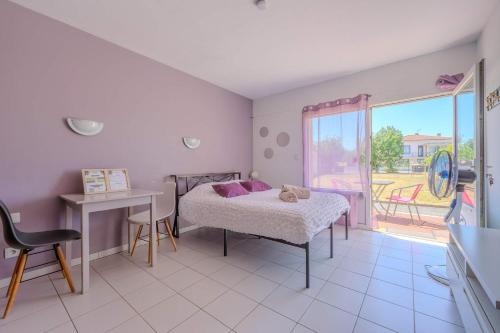 a bedroom with a bed and a table and a window at Appartement Lilas - Résidence Kiwi in Aytré