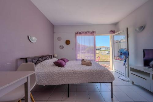 a bedroom with a bed with purple pillows and a window at Appartement Lilas - Résidence Kiwi in Aytré