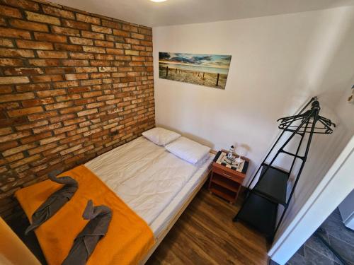 a small bedroom with a brick wall and a bed at Przystanek Żarnowska Domki in Żarnowska