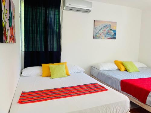 two beds in a room with a red and yellow blanket at Economic Apartments & Rooms next to the beach in Cancún