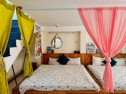 two beds in a bedroom with pink and yellow curtains at Annie.homestay 12NM in Nha Trang