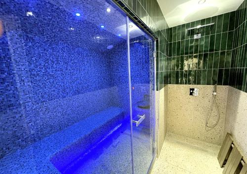 a bathroom with a blue shower with a bench in it at Spa Privatif Montataire in Montataire