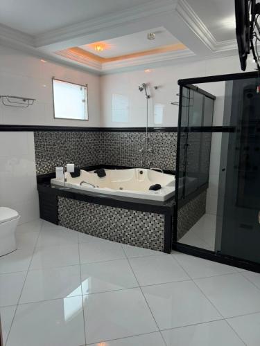 a bathroom with a bath tub and a toilet at Mansão Bolsoni in Saquarema