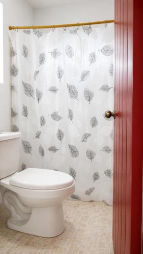 a bathroom with a toilet and a shower curtain with umbrellas at Casa Bugambilias in Tenosique de Pino Suárez