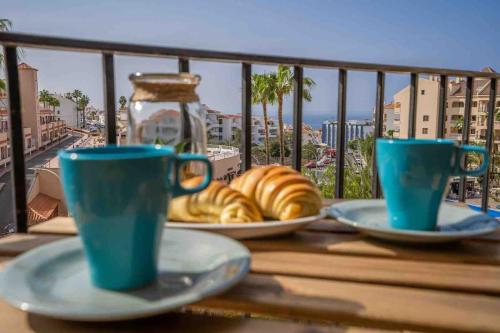a table with plates of croissants and cups on a balcony at Noemi Blu Tenerife in Los Cristianos