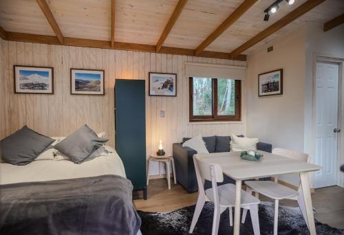 a bedroom with a bed and a table with chairs at Tagua Cabins Malalcahuello in Malalcahuello