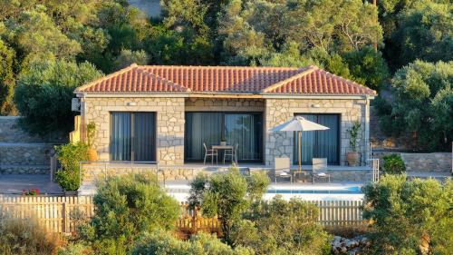a small stone house with a table and an umbrella at Ionian Harmony Luxury Villas in Tsoukalades