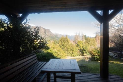 a wooden bench sitting on a porch with a view at Arelauquen Bungalows & Suites in San Carlos de Bariloche