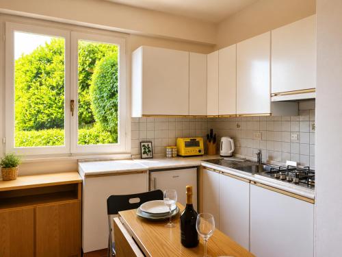 a kitchen with white cabinets and a table with wine glasses at Casa Leima - Larihome A83 in Gera Lario