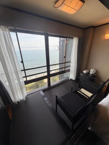 a room with a chair and a view of the ocean at HOTEL&RESORT Izu no Ne in Higashiizu