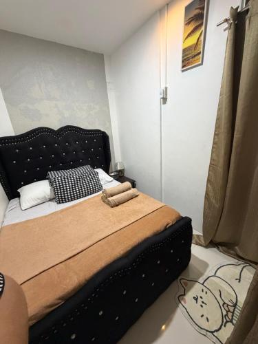 a bedroom with a bed with a black head board at My Humble Home in Dipolog