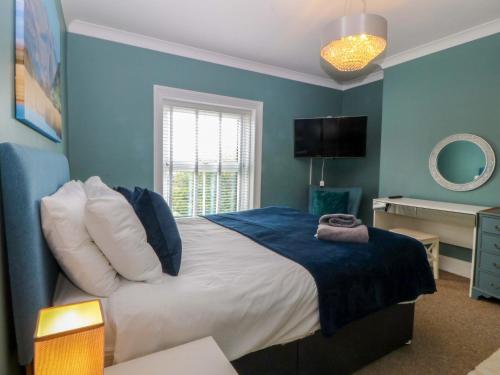 a bedroom with a bed with a blue wall at Jack's House in Tywyn