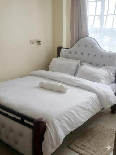 a bedroom with two beds with white sheets and a window at Sky-Host, Dulham suite in Homa Bay