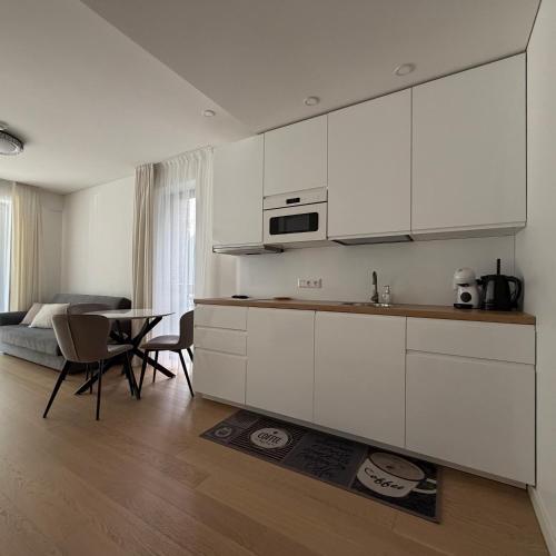 a kitchen with white cabinets and a table and a bed at Nerija in Juodkrantė
