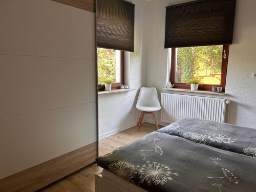 a bedroom with a bed and two windows and a chair at Ferienwohnung im Wesertal in Hameln
