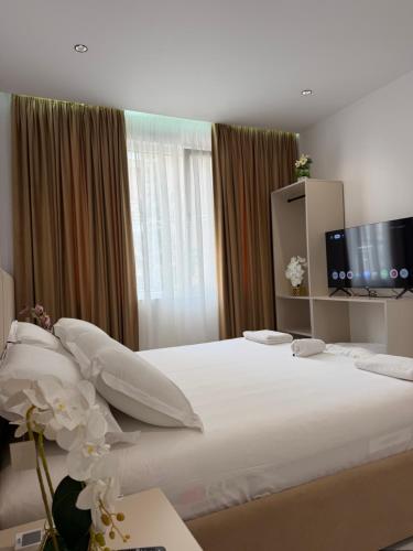 a bedroom with a large white bed with a flat screen tv at Hotel Djakbe in Tirana