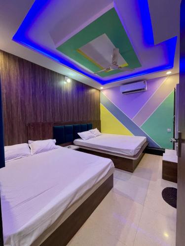 two beds in a room with a colorful ceiling at Hotel sagar inn in Ajmer