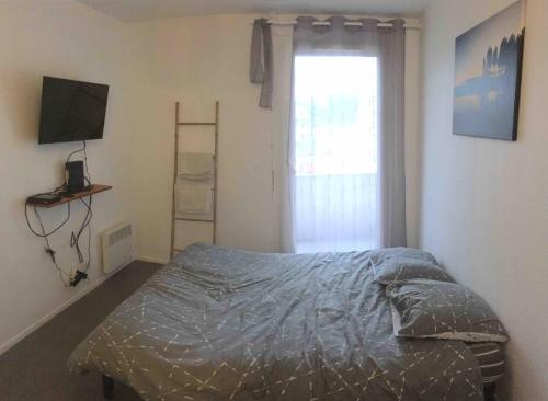 a bedroom with a bed with a television and a window at Studio BRITTANY in Chambéry