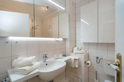 a white bathroom with a sink and a mirror at Syltliebe in Westerland