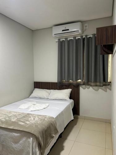 a bedroom with a bed and a window with curtains at Hotel 2001 in Iraí de Minas