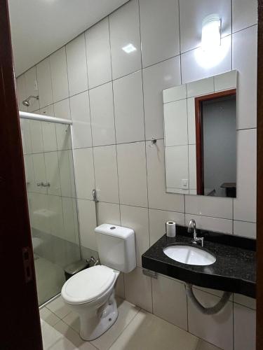 a bathroom with a toilet and a sink and a mirror at Hotel 2001 in Iraí de Minas