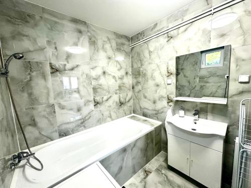 a bathroom with a white tub and a sink at Liliput Apartman in Sarkad