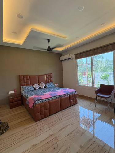 a bedroom with a large bed and a large window at La Vida Estate Farm in Garhmuktesar