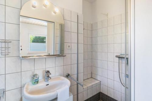 a white bathroom with a sink and a shower at Haus Achtern Diek - Ferienwohnungen in Wangerland