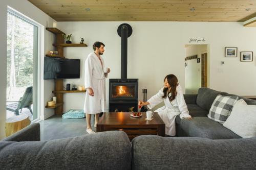 a man and woman in a living room with a fireplace at Chalet la coulée douce, Expérience thermale privée in Saint Come