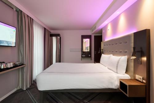a bedroom with a white bed and a tv at Premier Inn Wolfsburg City Centre in Wolfsburg
