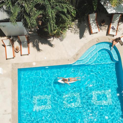 a person swimming in a pool with a water slide at Tribe Boutique Hotel - Adults Only in Dominical