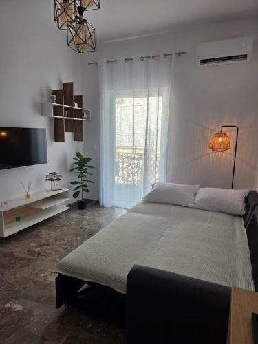a white bedroom with a large bed and a window at Loutraki Cozy Loft in Loutraki