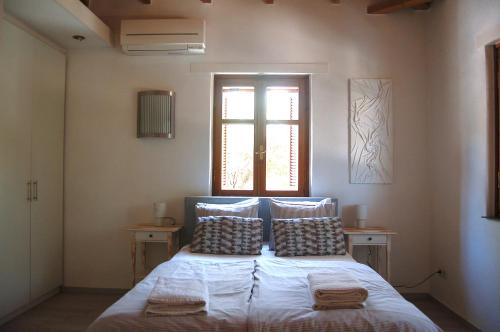 a bedroom with a bed with pillows and a window at The Art House in Kotrónion