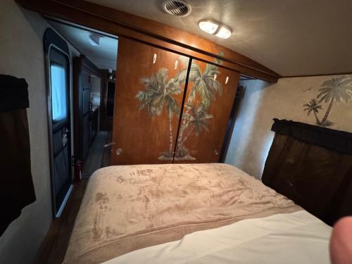 a bed in a room with a painting of palm trees at Florida VIBE in Homosassa Springs
